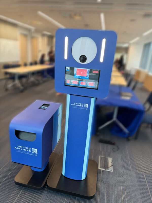 Totem de fotos United Airlines em evento corporativo, registrado pela PhotoA, com impressão instantânea e personalização para participantes.